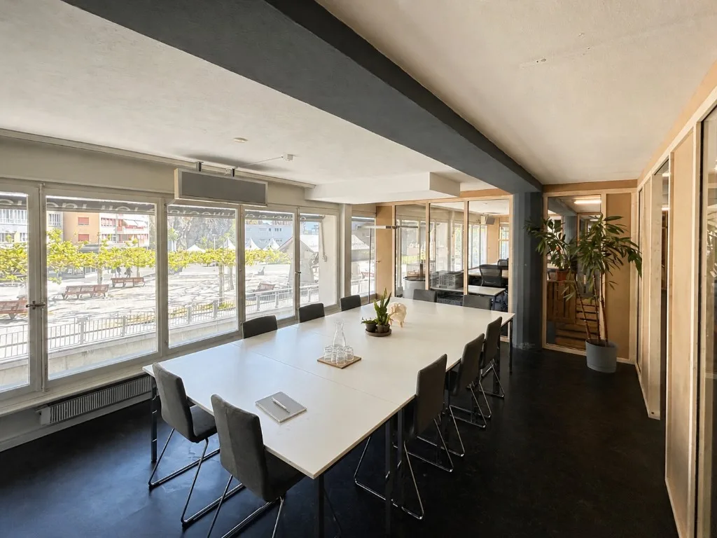 Meeting room in Sion with large table, windows on Place du Midi and glass offices
